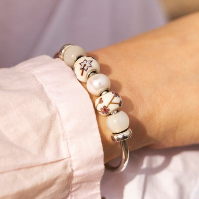 Close-up of a person wearing a bracelet with white beads and a blurred background