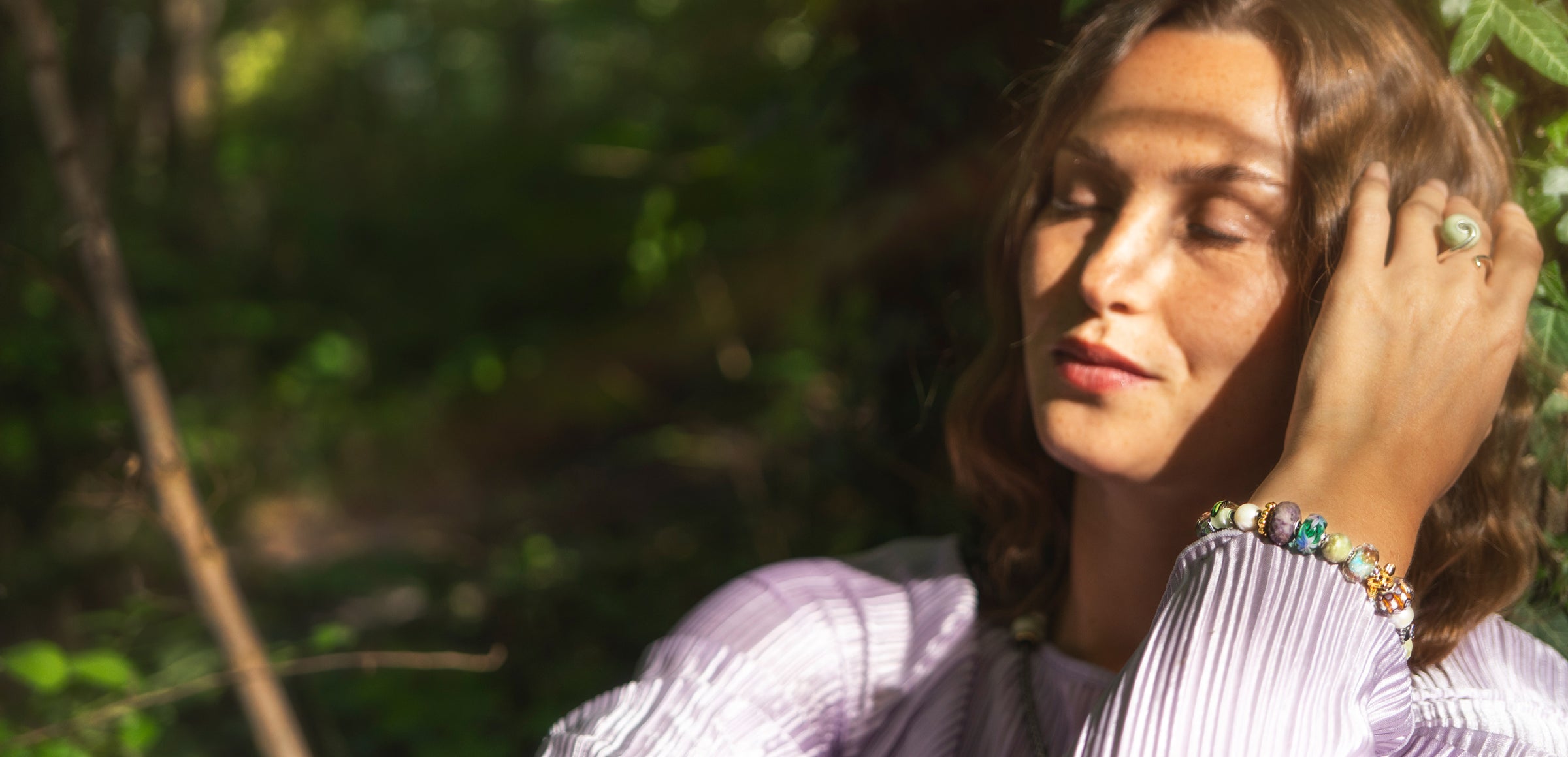 Model med ring og armbånd fra Trollbeads med kugler i lilla, grønne guld og blå nuancer